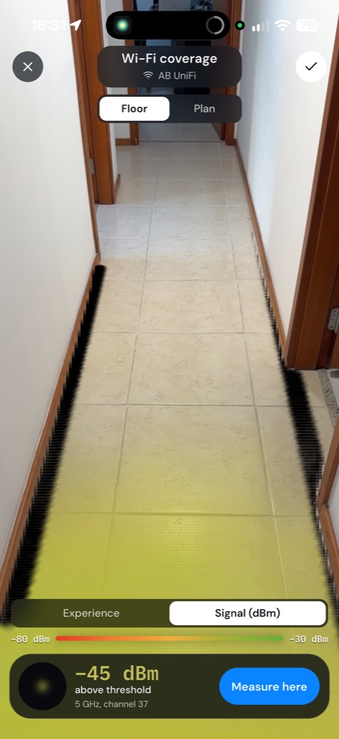 A tela do app no corredor: pela câmera, o chão pintado na cor do sinal medido, com o nível do sinal embaixo.